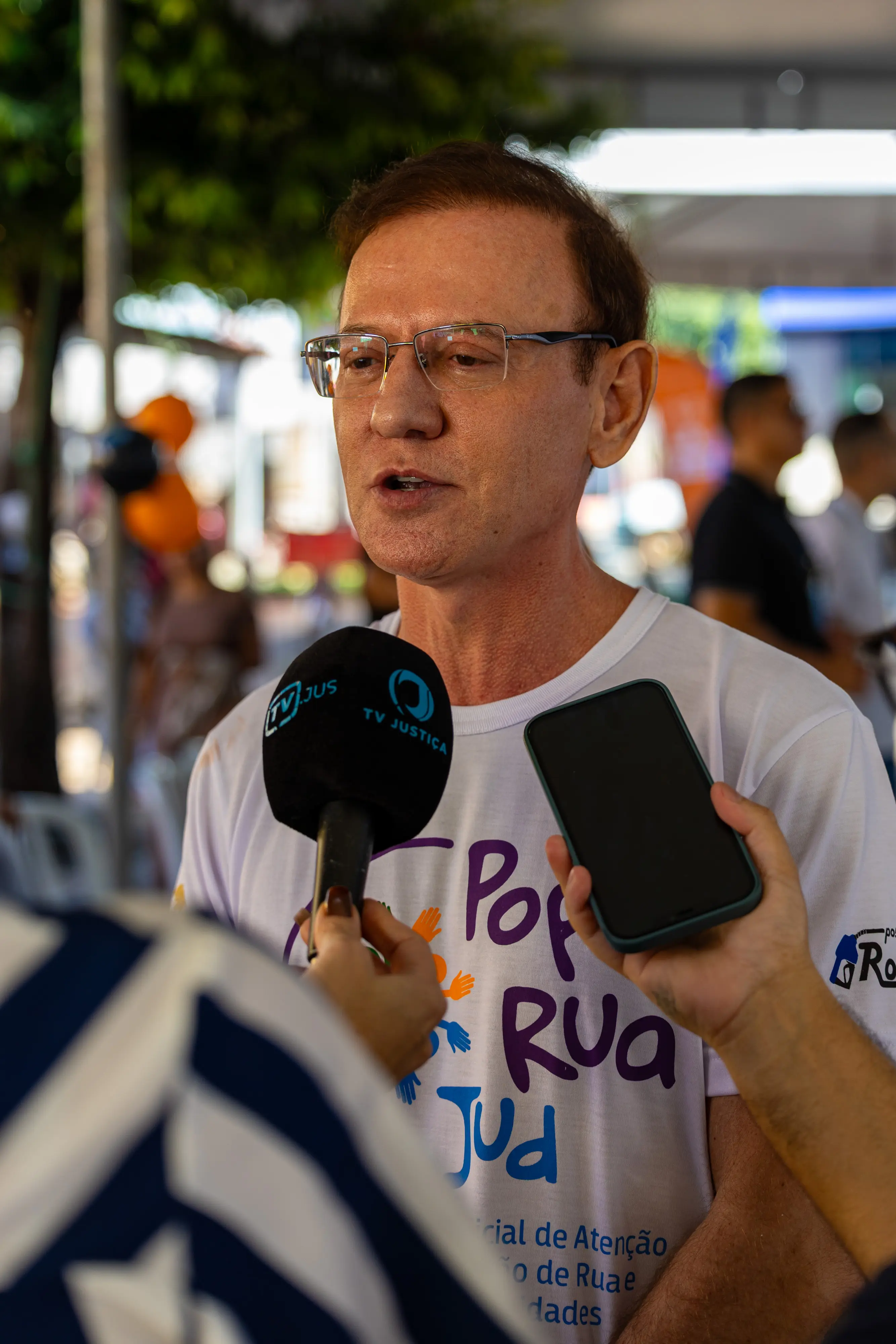 Homem de óculos e camiseta branca com logo 
