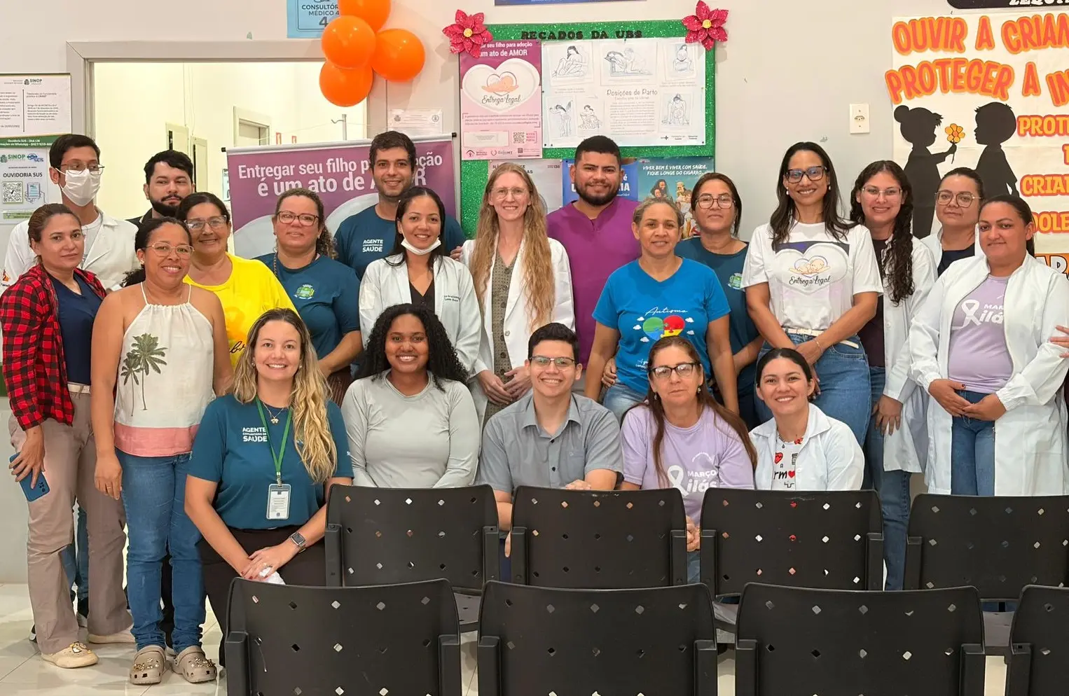 A imagem mostra um grupo de 19 pessoas reunidas em um ambiente interno, posando para uma foto de equipe.