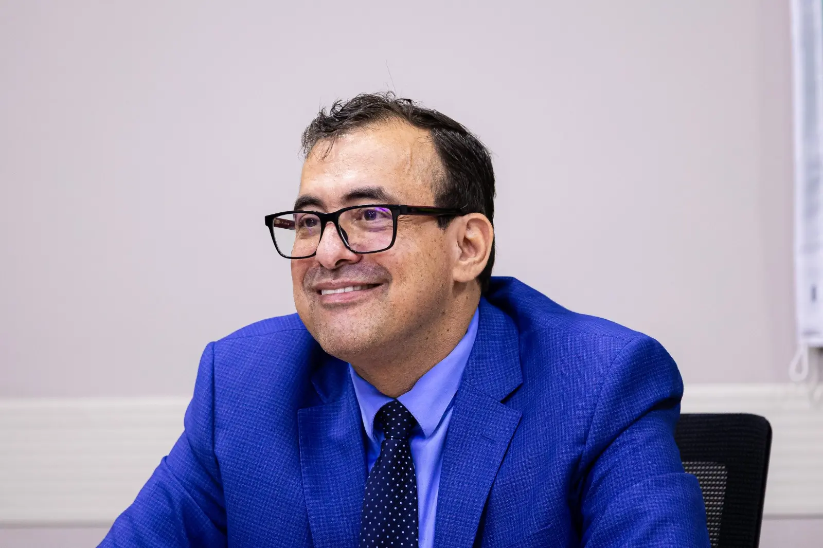 O juiz auxiliar, Jorge Alexandre Martins Ferreira, aparece sentado durante o lançamento da Copa do Judiciário 2026. Ele veste terno azul, camisa azul-clara e gravata escura, além de óculos de armação preta.