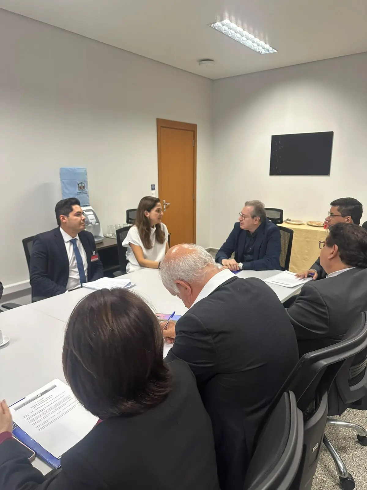 Foto vertical que mostra diversas pessoas sentadas em volta de uma mesa retangular, durante reunião do Conselho de Supervisão dos Juizados com representantes da OAB-MT.
