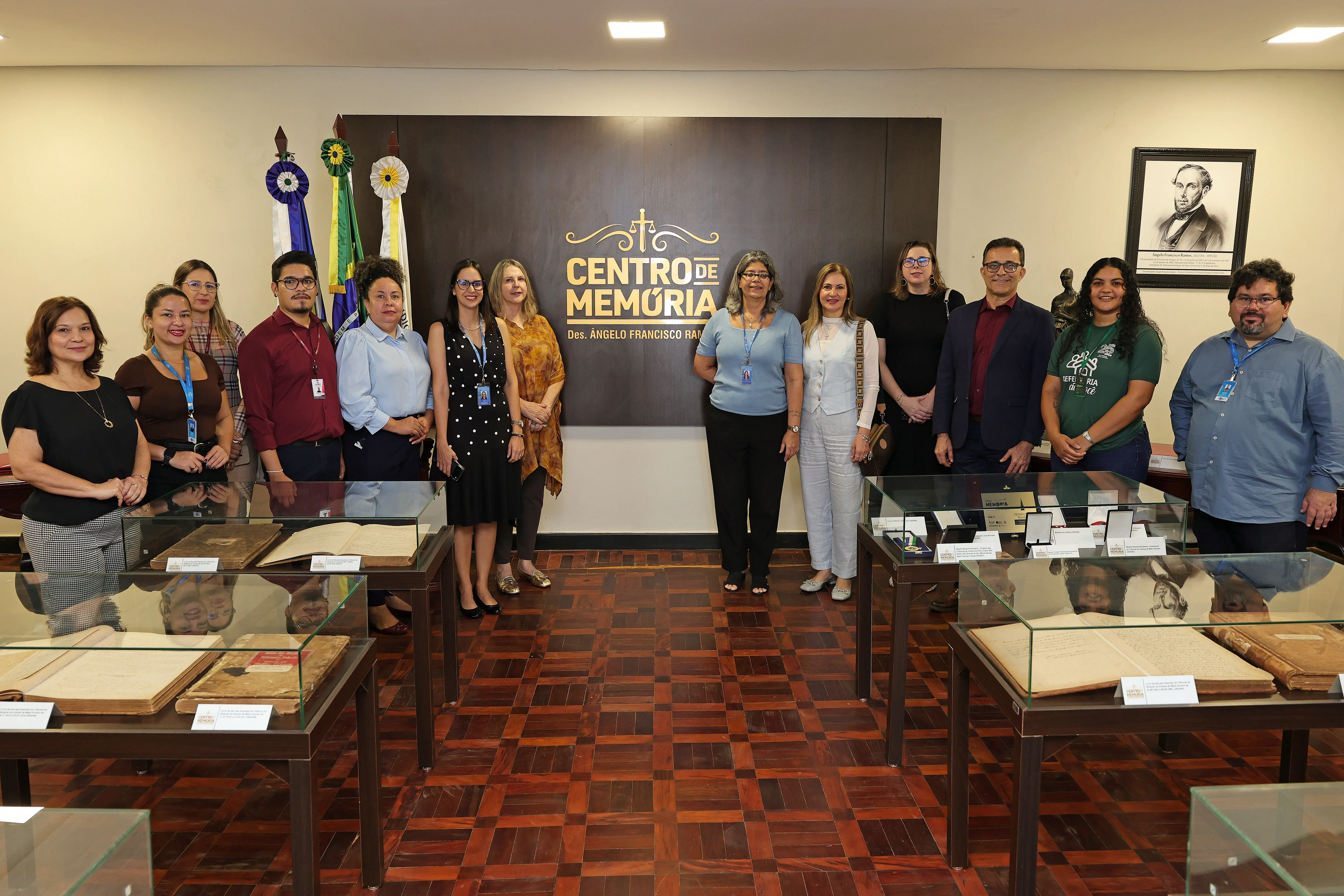 Um grupo de pessoas está reunido em frente a um painel com o logotipo 