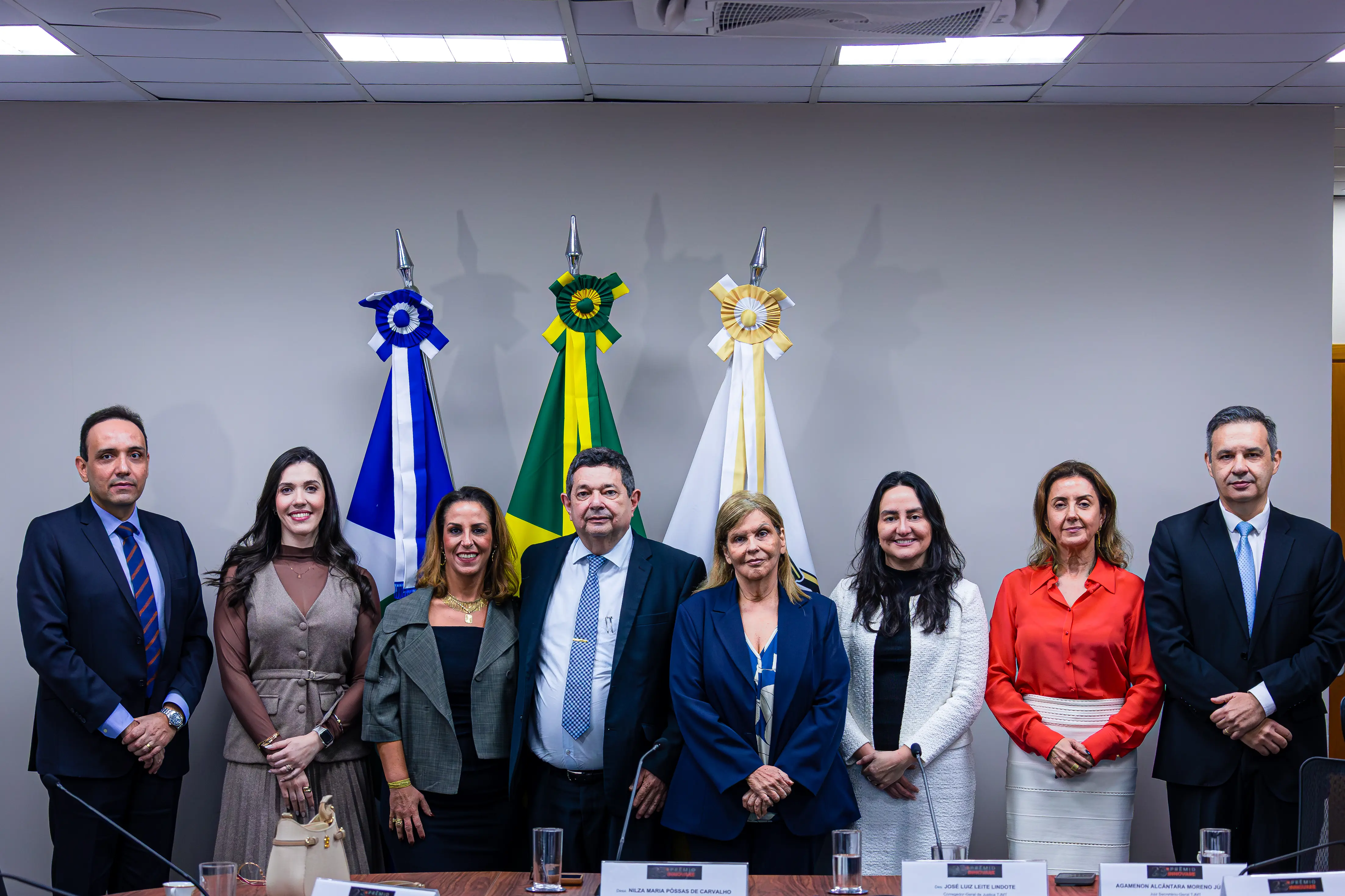 Grupo de oito pessoas perfiladas durante visita da consultora do Prêmio Innovare ao TJMT para conhecer os projetos selecionados. São três homens e cinco mulheres vestidos elegantemente. 